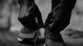 A close-up, black-and-white image showing hands tying shoelaces