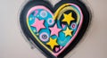 Colorful chalk and star shapes create a playful heart design on a chalkboard surface