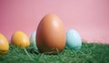 colorful easter eggs with blue , yellow, and egg color on green grass with pink background