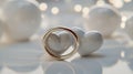 A gold wedding ring is positioned in front of smooth, glossy white ceramic hearts Royalty Free Stock Photo