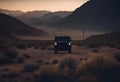 a jeep driving across a dirt field near mountains at sunset