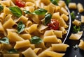 a black plate topped with pasta next to spinach and tomatoes