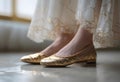 the feet of a woman in shiny gold ballet shoes standing on the floor Royalty Free Stock Photo