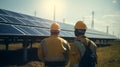 workers in helmets look at the array of solar panels on the roof