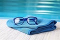 AI generated illustration of a pair of blue sunglasses rests on the edge of a swimming pool