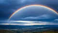 a rainbow over a hill with a dark cloud in the sky Royalty Free Stock Photo