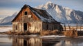 Old barn and mountains reflected in water.