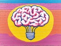 Bright yellow and pink mural of a glowing brain shaped lightbulb symbolizing intelligence and creativity set against a vivid