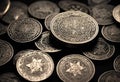 many shiny coins are piled together on the table next to a glass Royalty Free Stock Photo