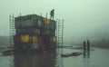 AI-generated illustration of stacked industrial containers submerged in the water in a foggy setting