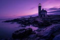 the sun sets behind a lighthouse on a rocky coast near water Royalty Free Stock Photo