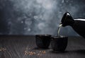 AI generated illustration of Tea being poured into two black cups on a wooden table. Royalty Free Stock Photo