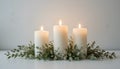 Trio of Lit White Pillar Candles in a Greenery and White Flower Centerpiece Royalty Free Stock Photo