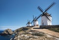 AI generated illustration of Three traditional-style windmills standing atop a hill