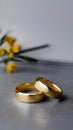 AI generated illustration of two gold wedding rings rest on a table among yellow flowers Royalty Free Stock Photo