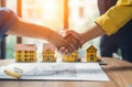 AI generated illustration of two people shaking hands in front of model houses Royalty Free Stock Photo