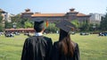 AI generated illustration of two young graduates in graduation gowns standing in a green field