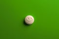 a white pill on top of a green surface of medicine