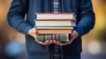 a person in a blue jacket holding a stack of books Royalty Free Stock Photo