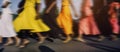 AI generated image. Motion blurred low section image of unrecognizable people wearing colorful dresses in the city