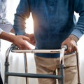 Doctor or nurse caregiver with senior man using walker assistance at nursing home