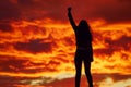 Female silhouette with a raised fist against the red sunset sky. Feminism and women quality concept