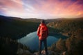 Ai generated image of a hiker on top of a mountain looking at an alpine lake
