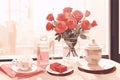 Still life painting of a vase of red roses, a teapot and two teacups on a table with a pink tablecloth, in a minimalist style, wi Royalty Free Stock Photo