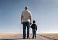 a man and a child are standing in the middle of a road.