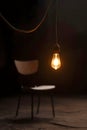 Quiet Solitude And Silent Waiting Beneath A Hanging Light Bulb And Empty Chair Royalty Free Stock Photo