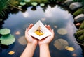 a person holds a paper boat with a yellow leaf floating in the water Royalty Free Stock Photo