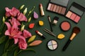 Makeup cosmetics and flowers on dark green background Royalty Free Stock Photo