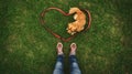 A small brown dog rests on grass, surrounded by a red leash arranged in a heart shape Royalty Free Stock Photo
