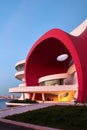 AI generated vibrant red curved building situated next to a body of water