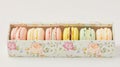 a box with beautiful pastel flower pattern, inside are six different colored macaroons in pastel color