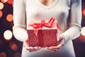 Ai generative. Christmas gift box with red ribbons in female hands Royalty Free Stock Photo