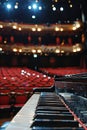 Close-up of a grand piano keyboard with theater seating in the background. Royalty Free Stock Photo