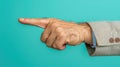 A man& x27;s hand pointing left with a thumbs-up gesture on a teal background. Royalty Free Stock Photo