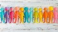 Paper cutout figures in multiple colors lined up on a distressed wooden background.