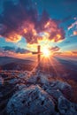 A radiant sunset behind a cross on a rocky mountain.