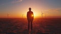 Silhouette of a man before wind turbines at sunset. Royalty Free Stock Photo