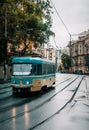 AI illustration of a blue trolley car traveling down a wet and bustling city street in the rain.