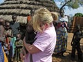 Aid relief worker holding starving hungry African baby in village Africa Royalty Free Stock Photo