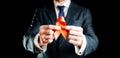 Aid ribbon silk. Red ribbon in hiv world day in man hand. Awareness aids and cancer symbol on black background. HIV Royalty Free Stock Photo