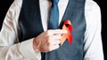 Aid ribbon silk. Red ribbon in hiv world day in man hand. Awareness aids and cancer symbol on black background. HIV Royalty Free Stock Photo