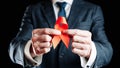 Aid ribbon silk. Red ribbon in hiv world day in man hand. Awareness aids and cancer symbol on black background. HIV Royalty Free Stock Photo