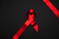 Aid ribbon silk. Red ribbon symbol in hiv world day on black background. Awareness aids and cancer. Flat lay, top view, copy space Royalty Free Stock Photo