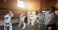 Aikido, group and class with sensei, weapon training and wooden sword for self defence exercise. Dojo, student or Royalty Free Stock Photo