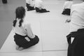 Aikido training participants sit on a mat