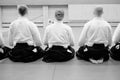 Aikido training participants sit on a mat